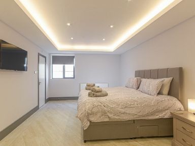 A bedroom with a double bed a window a wall-mounted television and a bedside table at Riverview Alnmouth