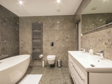 A bathroom with a bathtub toilet double sink and large mirror at Riverview Alnmouth