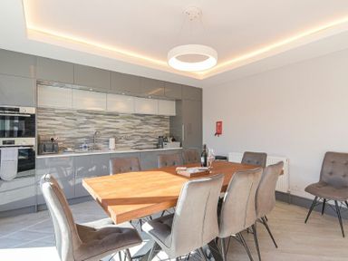 A kitchen with a wooden dining table surrounded by gray chairs at Riverview (Alnmouth) in Alnmouth