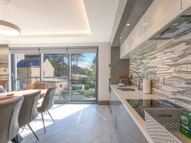A kitchen and dining area with chairs around a table and large windows at Riverview Alnmouth