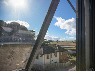 A view from a window showing rooftops a fence trees and fields at Riverview Alnmouth