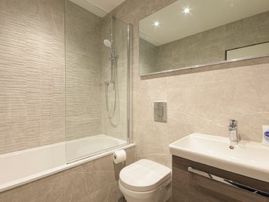 A bathroom with a bathtub shower combo toilet and sink at Riverview Alnmouth