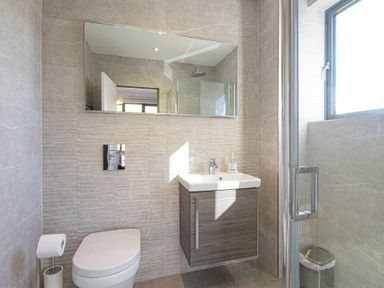 A bathroom with a toilet sink mirror shower and window at Riverview (Alnmouth) in Alnmouth