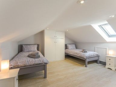 A bedroom with two single beds and a built in wardrobe under a slanted ceiling at Riverview Alnmouth