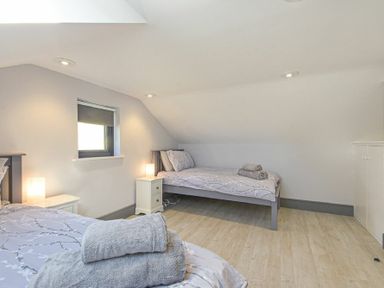 A bedroom with two single beds bedside tables with lamps and towels on the beds at Riverview Alnmouth