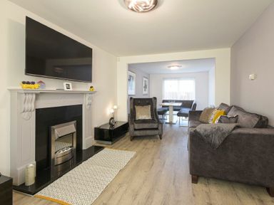 A living room with a fireplace television armchair sofa and dining area at Coastal View in Seahouses