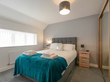 A bedroom with a bed a bedside table and a window at Coastal View in Seahouses