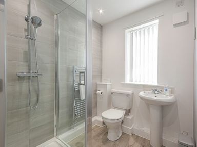 A bathroom with a shower enclosure toilet sink and a window at Coastal View in Seahouses