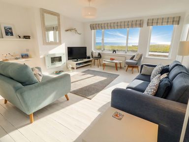 A living room with a television and sofas at Dell Point in Beadnell
