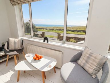 A snug with a table and chairs overlooking the sea at Dell Point Beadnell