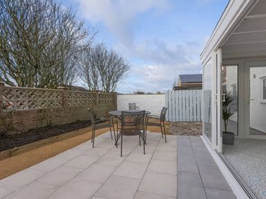 A garden with outdoor seating and a fence at Dell Point in Beadnell