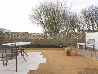 A garden with a table and chairs at Dell Point Beadnell