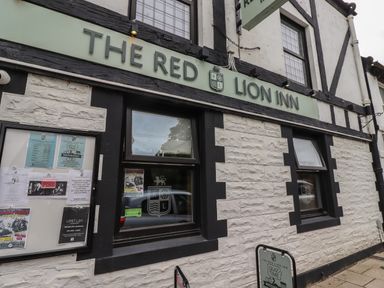 Exterior of a building with sign reading The Red Lion Inn and windows with notices on the wall at The Red Lion Inn in Alnmouth