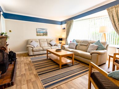 A living room with two leather sofas a wooden coffee table a striped rug and a fireplace at Palmers Rest in Beadnell