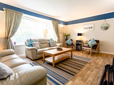 A living room with beige sofas a wooden coffee table and a striped rug at Palmers Rest in Beadnell