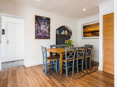 A dining room with a wooden table and eight chairs with a vase of flowers on the table at Palmers Rest in Beadnell