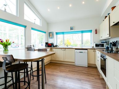 A kitchen with wooden floors wooden countertop cream cabinets and blue window blinds at Palmers Rest in Beadnell