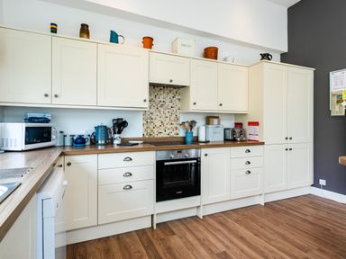 A kitchen with cream cabinets wooden countertops and various appliances including a microwave kettle and oven at Palmers Rest in Beadnell