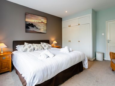 A bedroom with a double bed bedside tables lamps and built in wardrobes at Palmers Rest in Beadnell