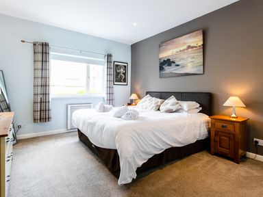 A bedroom with a bed pillows lamps and artwork on walls at Palmers Rest in Beadnell