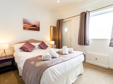 A bedroom with a bed with rolled towels pillows bedside tables and lamps at Palmers Rest in Beadnell