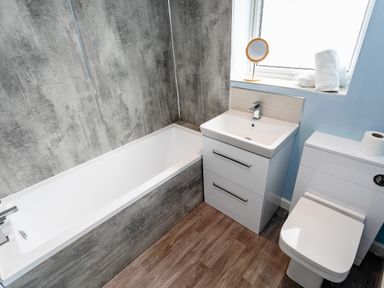 A bathroom with a bathtub sink toilet and a window with towels and a mirror at Palmers Rest Beadnell
