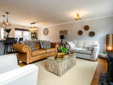 A living room with two sofas a coffee table and decorative wall hangings at Polished Pebble in Beadnell