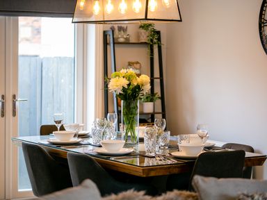 A dining room with a set table and flowers on the table at Polished Pebble in Beadnell