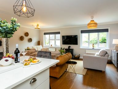 A living room with sofas a television and snacks on a kitchen counter at Polished Pebble in Beadnell