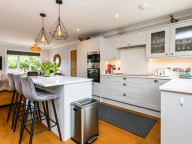 A kitchen with stools around an island and built in appliances at Polished Pebble in Beadnell