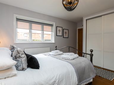 A bedroom with a metal bed frame pillows folded towels and a window at Polished Pebble in Beadnell