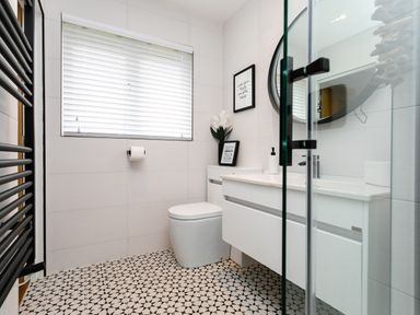 A bathroom with a toilet sink vanity mirror and patterned floor tiles at Polished Pebble in Beadnell