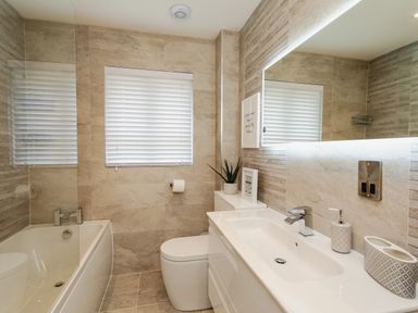 A bathroom with a bathtub toilet sink mirror and window blinds at Polished Pebble in Beadnell