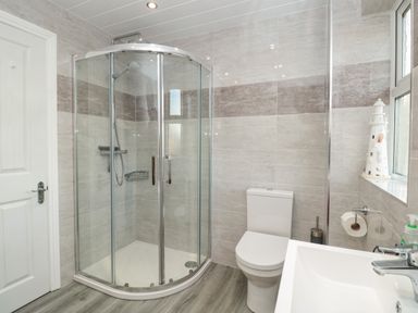A bathroom with a glass shower enclosure toilet and sink at Creel Cottage Blackwood Street Amble