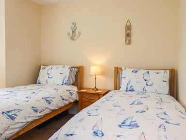 A bedroom with two single beds and a nightstand with a lamp at Creel Cottage Blackwood Street in Amble