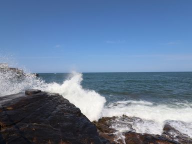 Waves crashing against rocks by the sea under a clear sky at Creel Cottage Blackwood Street in Amble