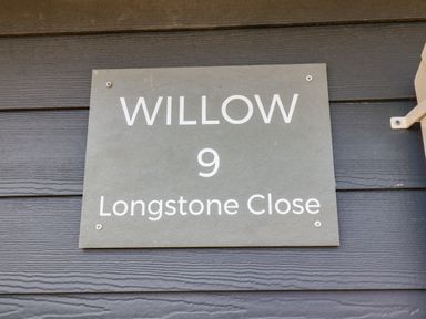 A house sign with text Willow 9 Longstone Close on a dark wall at Willow in Beadnell
