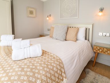 A bedroom with a bed with white and beige bedding and pillows bedside tables with lamps at Willow in Beadnell