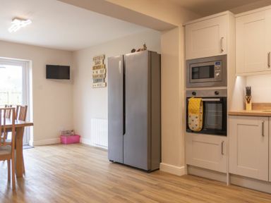 A kitchen with wooden dining table chairs stainless steel fridge built in oven and microwave at Southfield Lodge in Seahouses