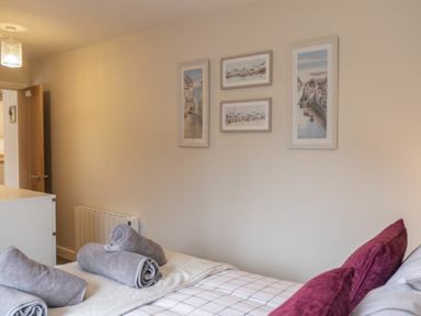 A bedroom with bed pillows rolled towels on the bed and framed pictures on the wall at Southfield Lodge in Seahouses