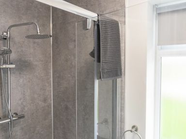 A shower area with a rainfall showerhead glass door and a towel hanging on the door at Southfield Lodge in Seahouses