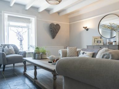 A living room with armchairs sofas a wooden coffee table and wall decoration at Creel Cottage Craster