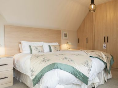 A bedroom with a double bed bedside tables lamps and built in wardrobes at Keepers View in Bamburgh