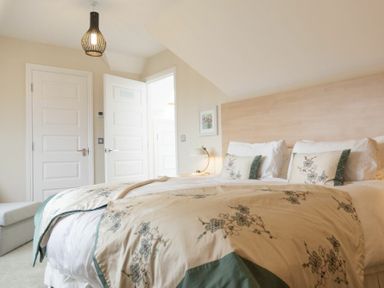 A bedroom with a bed a bedside lamp and two white doors at Keepers View in Bamburgh