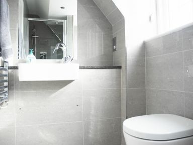 A bathroom with a toilet a sink a mirror and a glass shower enclosure at Keepers View in Bamburgh