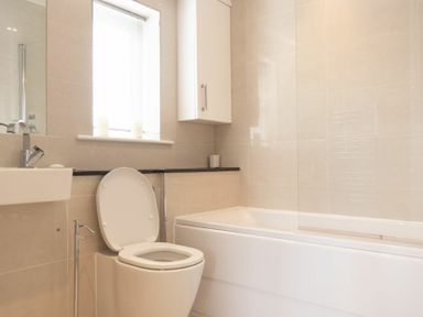 A bathroom with a toilet a bathtub a sink and a window at Keepers View in Bamburgh