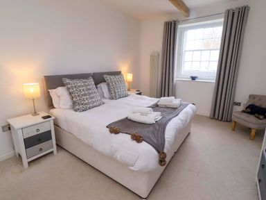 A bedroom with a bed and a bedside table at Treetops, Alnwick