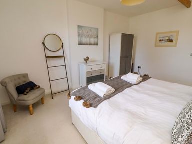 A bedroom with a bed and dresser at Treetops, Alnwick