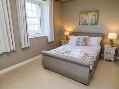 A bedroom with a bed and side tables at Treetops, Alnwick
