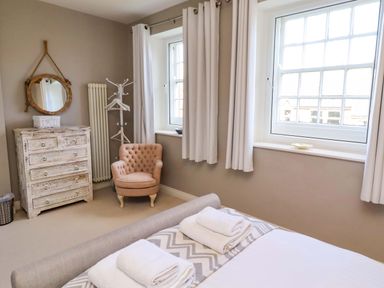 A bedroom with a bed and armchair at Treetops, Alnwick